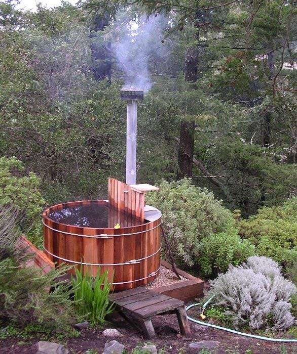 Outdoor wood-fired cedar barrel hot tub in the woods
