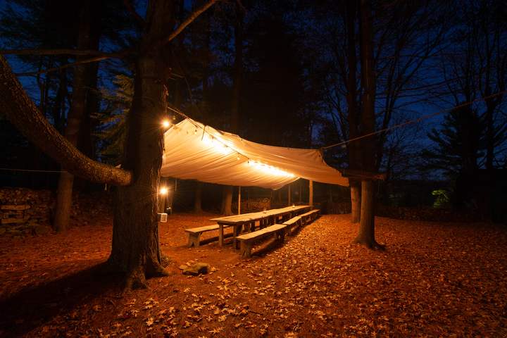 Long dinner table under a canopy at night, string lights