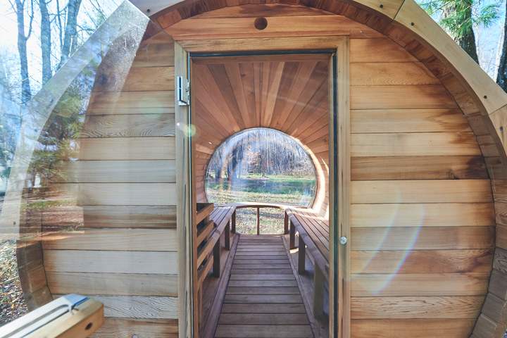 Wood-fired barrel sauna interior overlooking the pond