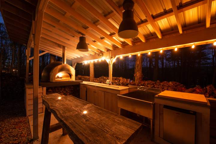 Outdoor wood-fired oven and kitchen at dusk